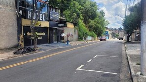 Eine Straße mit dem Hotel 'Hotel Bousada' auf der linken Seite, einer klaren Fahrbahn und einem geparkten Auto in der Ferne.