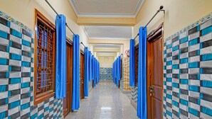 A hallway with blue curtains, checkered walls, and a tiled floor. - Classic With Balcony Diamond Inn (Durgapur)