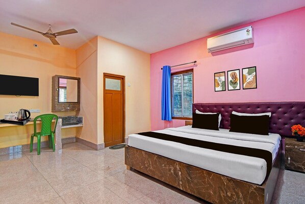 A hotel room with a bed, a desk with a chair, an air conditioner, a ceiling fan, a window with curtains, and artwork on the wall. - Classic With Balcony Diamond Inn (Durgapur)