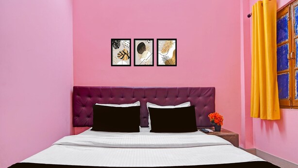 A bed with a purple headboard, white bedding, and two black pillows. There are three framed artworks on the wall above the bed. - Classic With Balcony Diamond Inn (Durgapur)