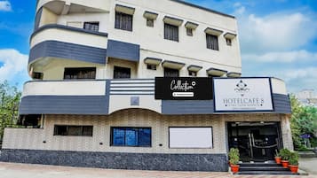 Un edificio de varios pisos con un letrero que indica 'HOTELCAFE 8' y 'Collection', señalando un hotel de servicios corporativos.