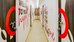 Un pasillo de hotel con puertas numeradas 101 y 106, y paredes con los mensajes 'WELCOME TO YOUR HAPPY PLACE' y 'EVERY FAMILY HAS A STORY'.