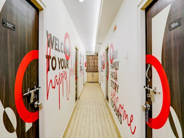 A hotel corridor with doors numbered 101 and 106, and walls with 'WELCOME TO YOUR HAPPY PLACE' and 'EVERY FAMILY HAS A STORY' messages.