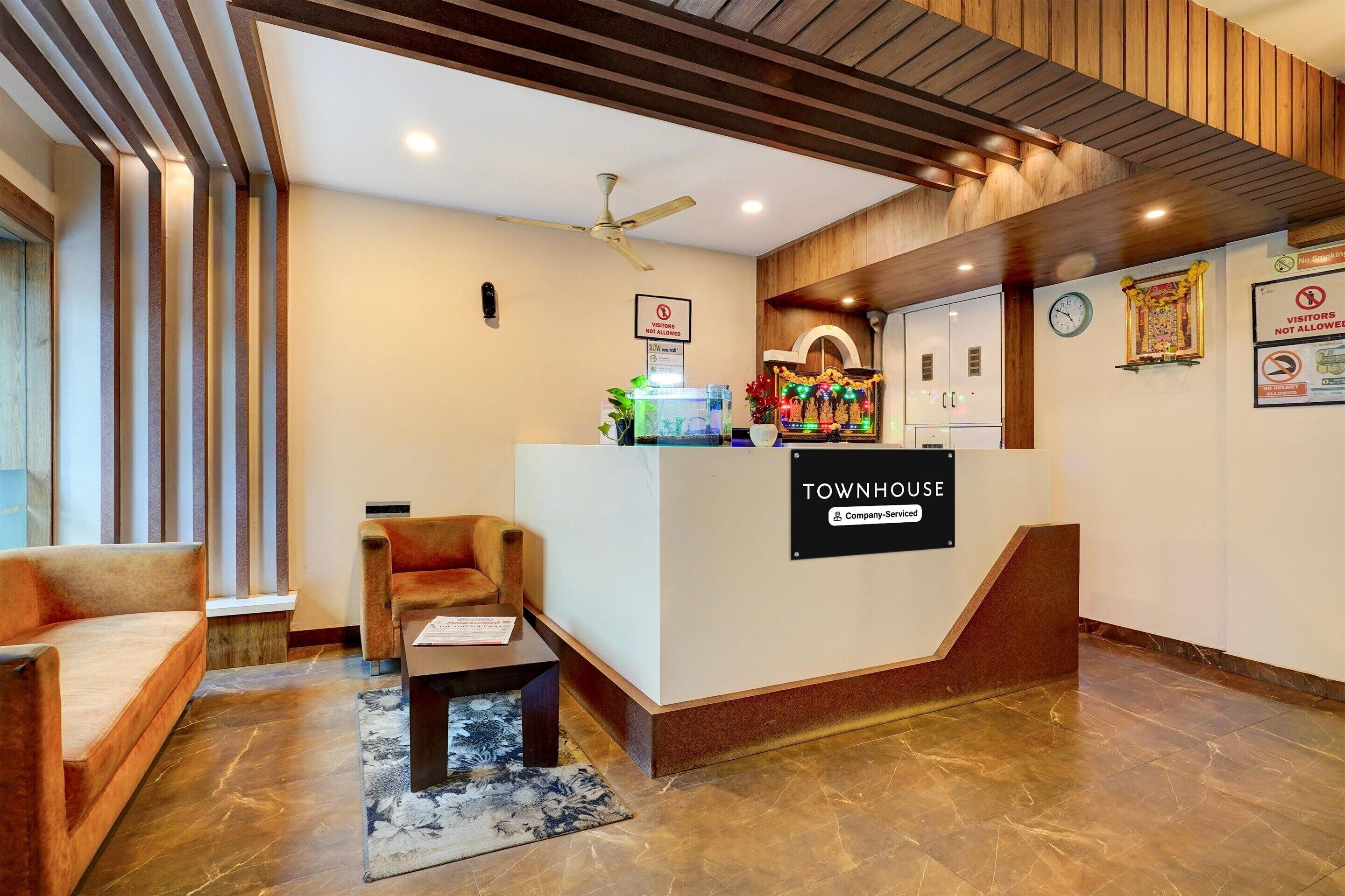 A reception area with a 'Townhouse' sign, a reception desk, a sofa, a chair, a clock, and a 'No Smoking' sign.
