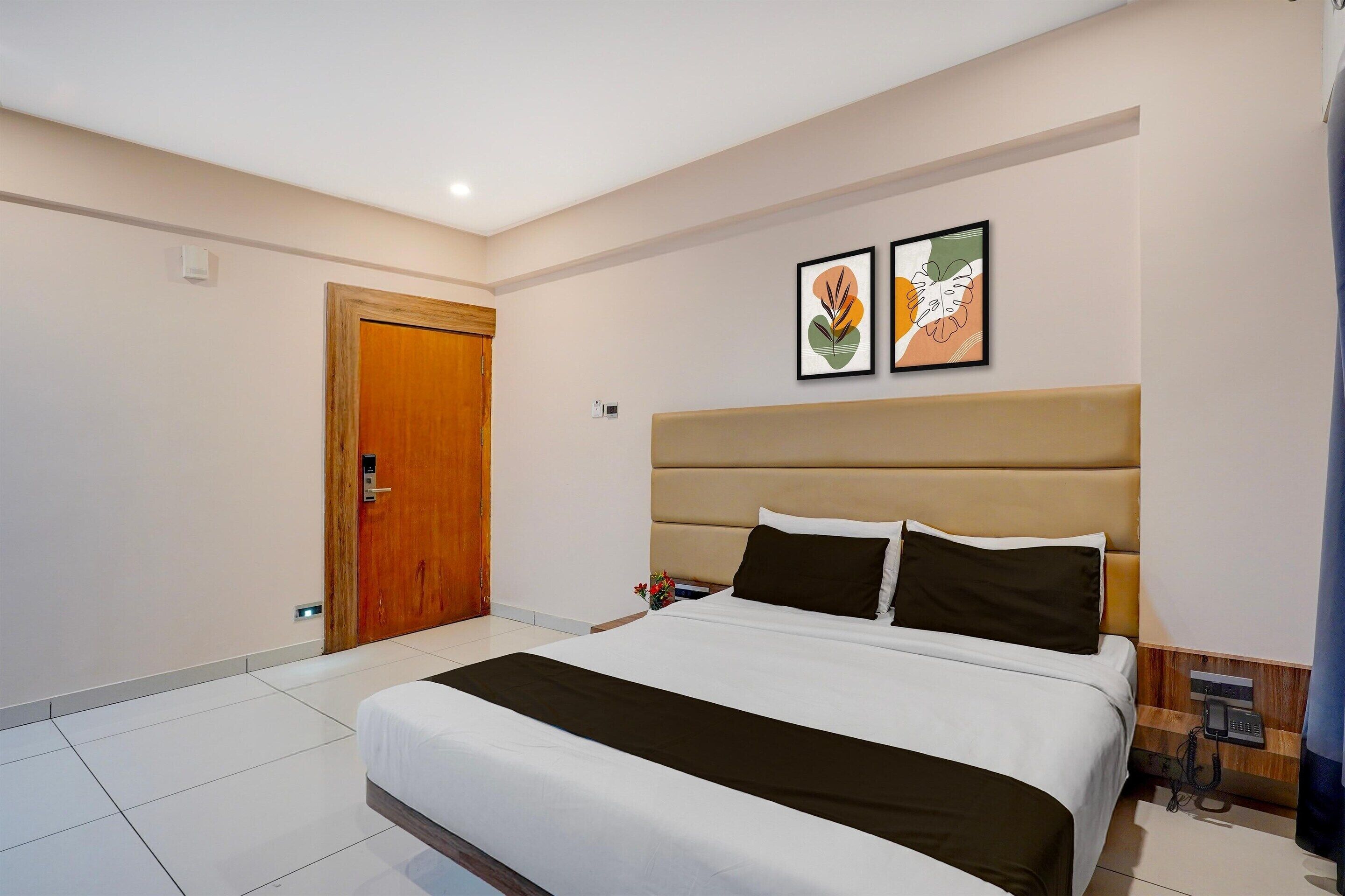 Une chambre d’hôtel avec un grand lit, une porte en bois et deux œuvres d’art encadrées au mur.