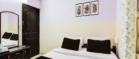 A hotel room with a bed, a dresser, a mirror, and three framed pictures on the wall.