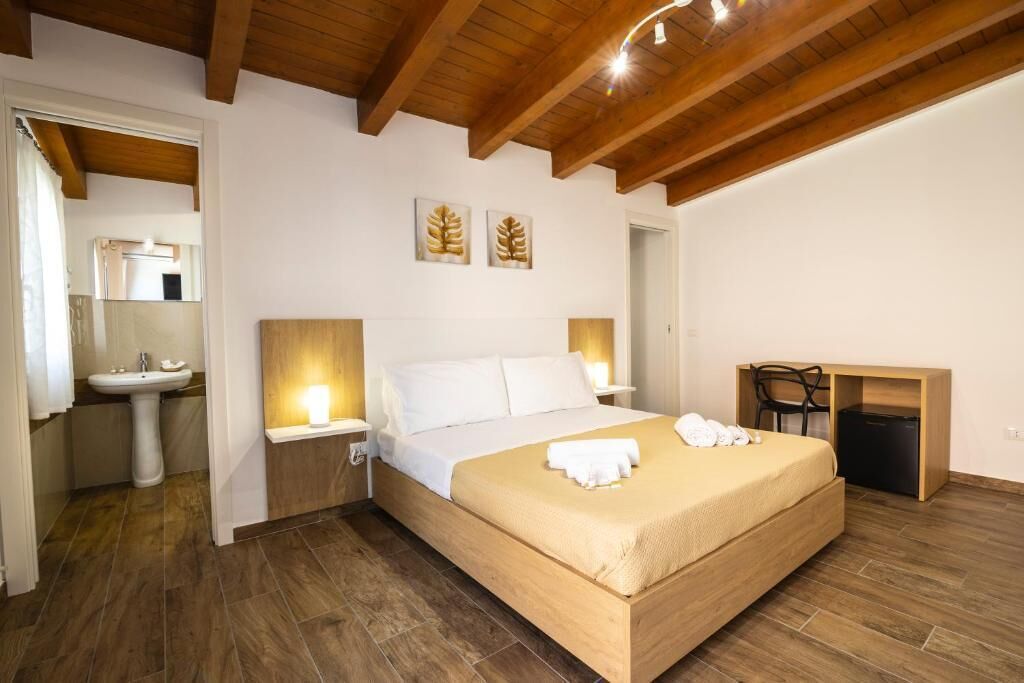 Una camera da letto con un letto, un comodino, una lampada e una scrivania con una sedia.