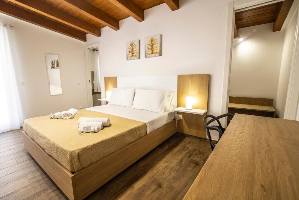 Una camera da letto con un letto, un comodino, una sedia e pavimento in legno.