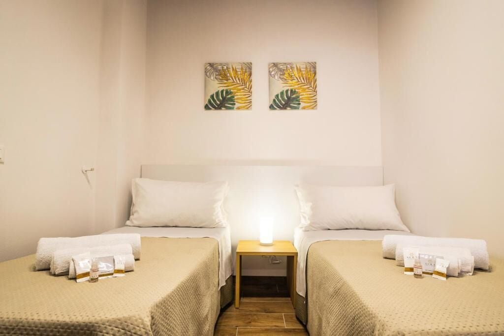 Une chambre d’hôtel avec deux lits, une table de chevet avec une lampe, des serviettes et des articles de toilette.