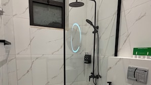 Ein modernes Badezimmer mit einer gläsernen Duschkabine, Toilette und Marmorboden.