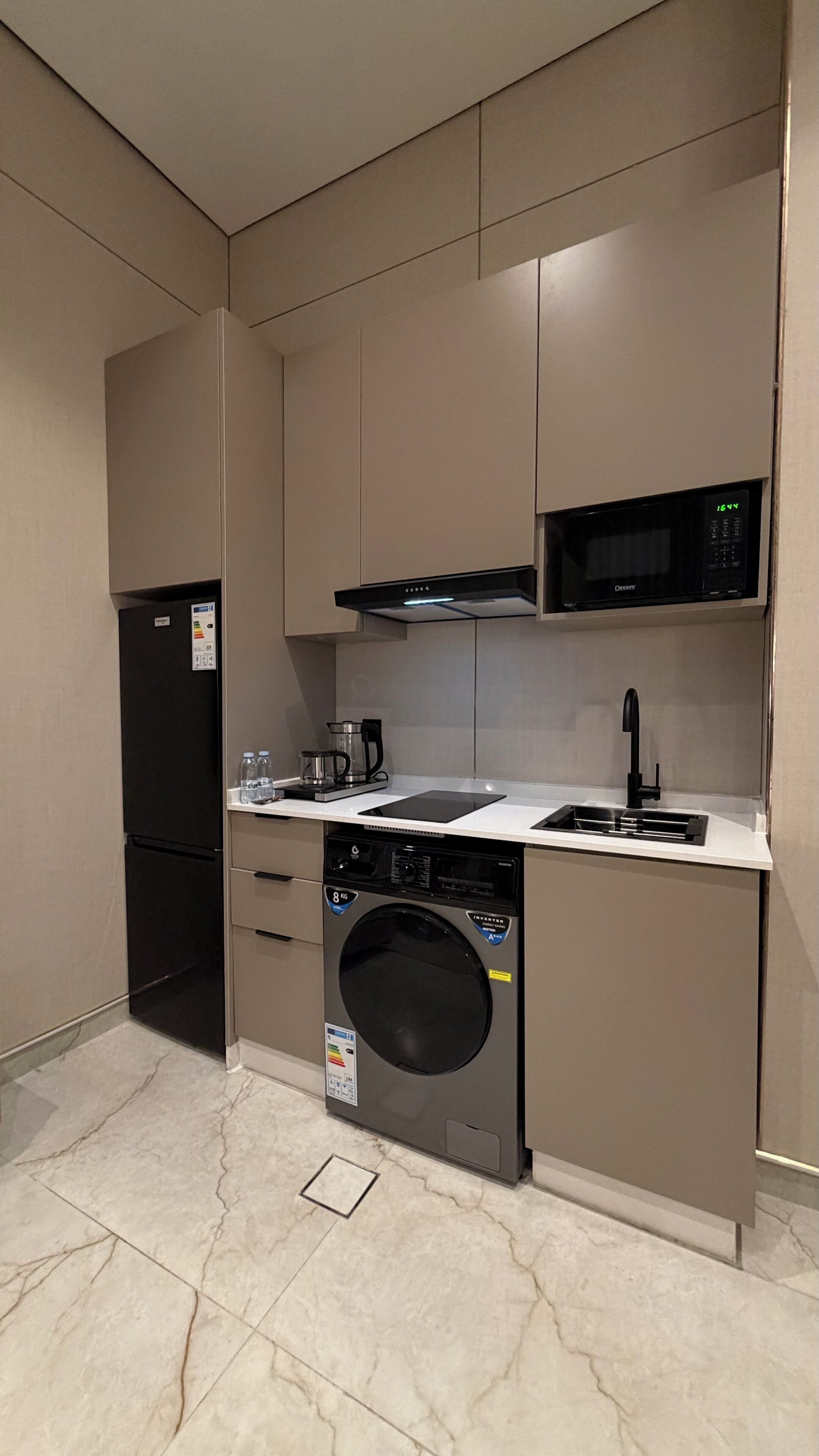 A compact kitchen with a built-in microwave, a coffee maker, a dishwasher, and a washing machine.