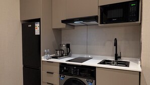 Eine kompakte Küche mit integriertem Mikrowellenherd, einer Kaffeemaschine, einem Geschirrspüler und einer Waschmaschine.