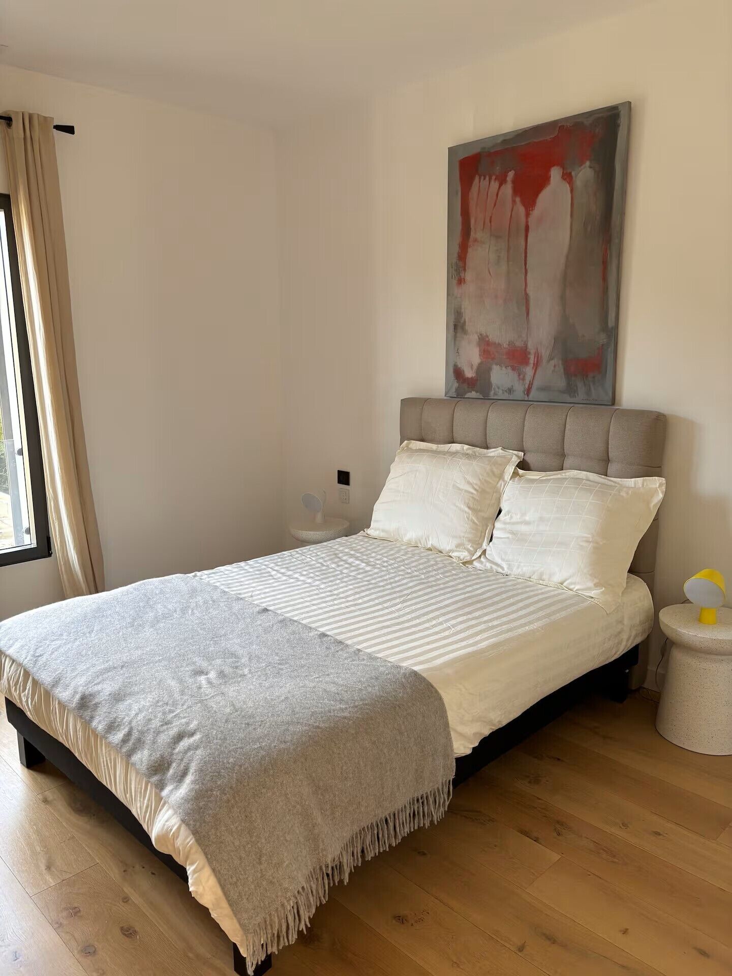 A bedroom with a bed, a bedside table, a lamp, and a painting on the wall.