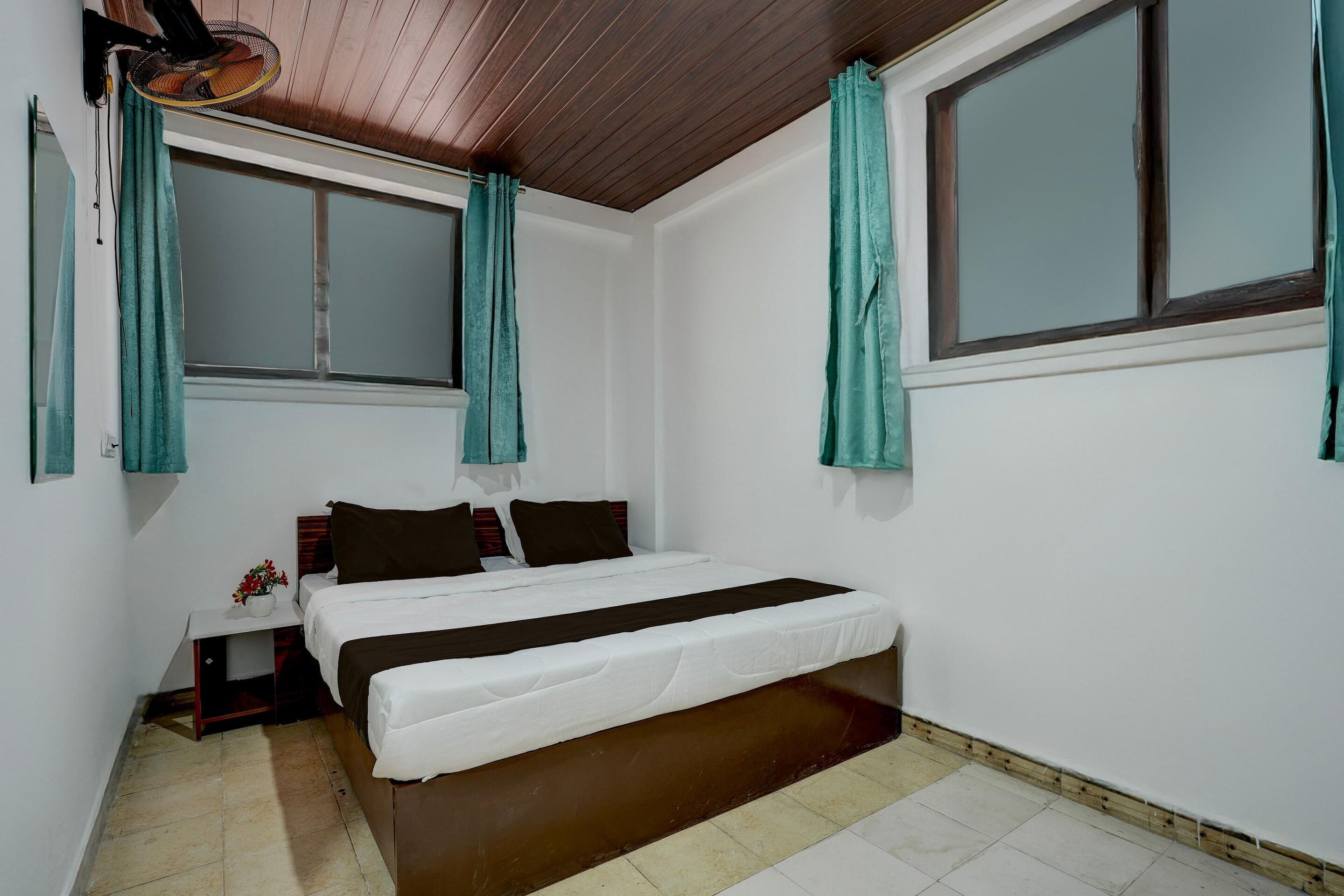 A bedroom with a bed, a nightstand, a window, and teal curtains.