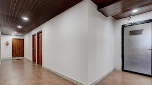 Un couloir avec des portes en bois, un extincteur et une porte en métal dotée d’une poignée.