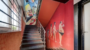 Un escalier avec une rampe, une fresque murale et une porte sur le côté droit.