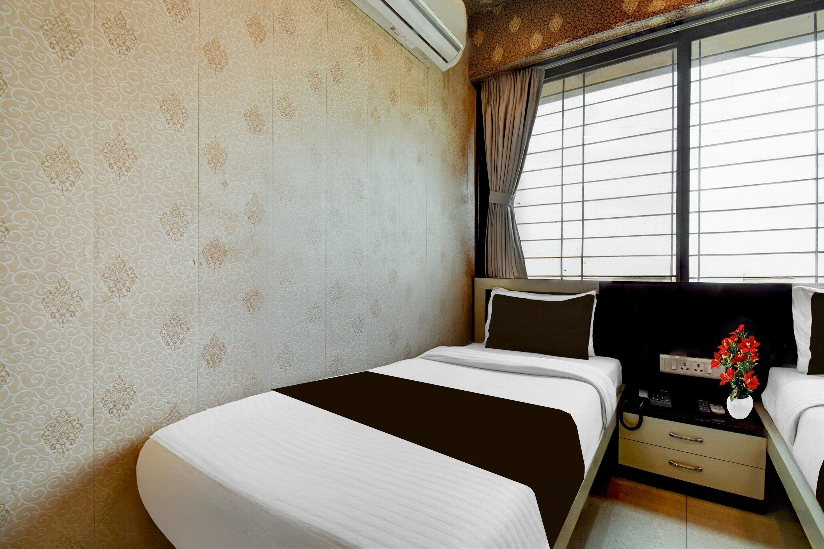 Une chambre d’hôtel avec un lit, une table de chevet et une fenêtre avec des rideaux.