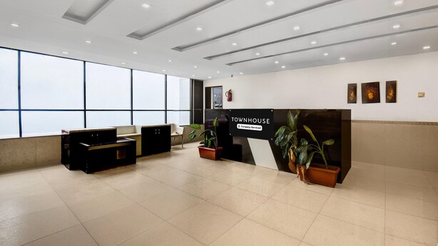 A reception area with a counter, potted plants, and a sign that reads 'TOWNHOUSE 5 Company Serviced.' - Classic With Balconymahalunge Ingale Pune (Rajgurunagar)