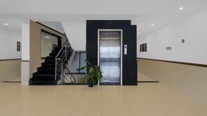 A modern lobby with a staircase, elevator, and a potted plant. - Classic With Balconymahalunge Ingale Pune (Rajgurunagar)