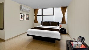 A hotel room with a large bed, a window with curtains, an air conditioning unit, and a tray with a coffee pot and cups. - Classic With Balconymahalunge Ingale Pune (Rajgurunagar)