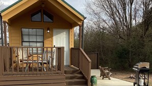 Une cabane avec une véranda, un garage et un foyer extérieur.