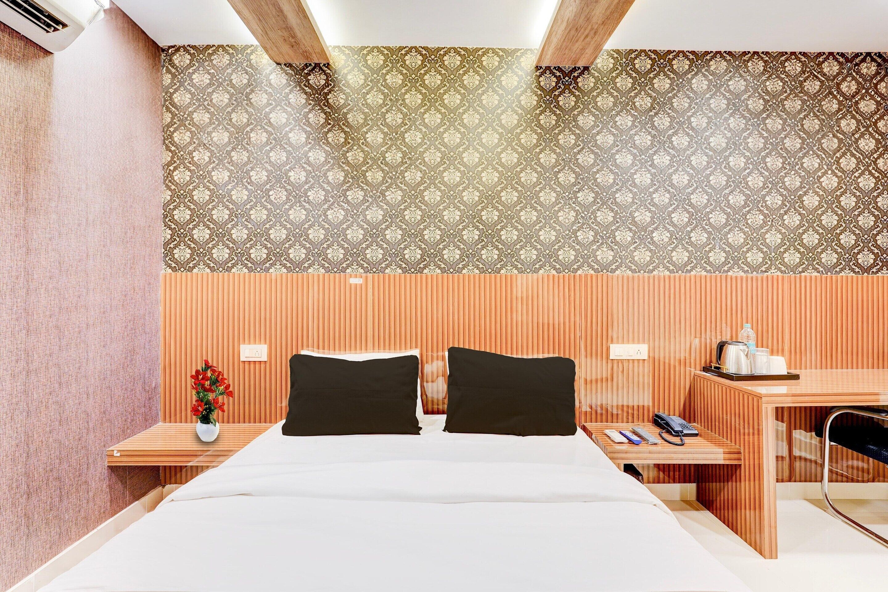 Ein Hotelzimmer mit einem Bett, zwei Nachttischen, einem Schreibtisch und einer Wand mit Muster.