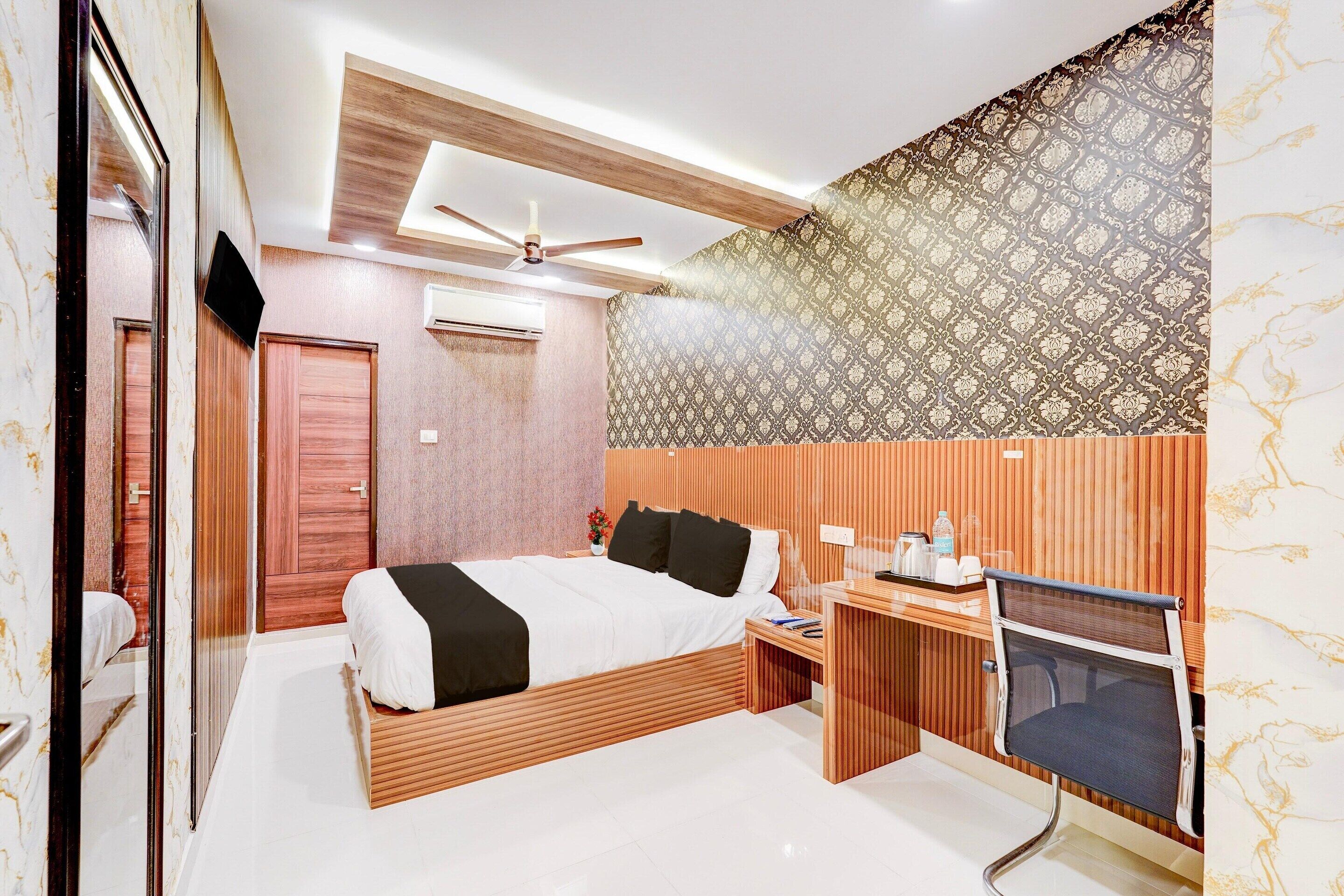 A bedroom with a bed, desk, chair, and a ceiling fan.