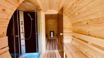 A wooden interior with a sauna, a glass door, and a bench.