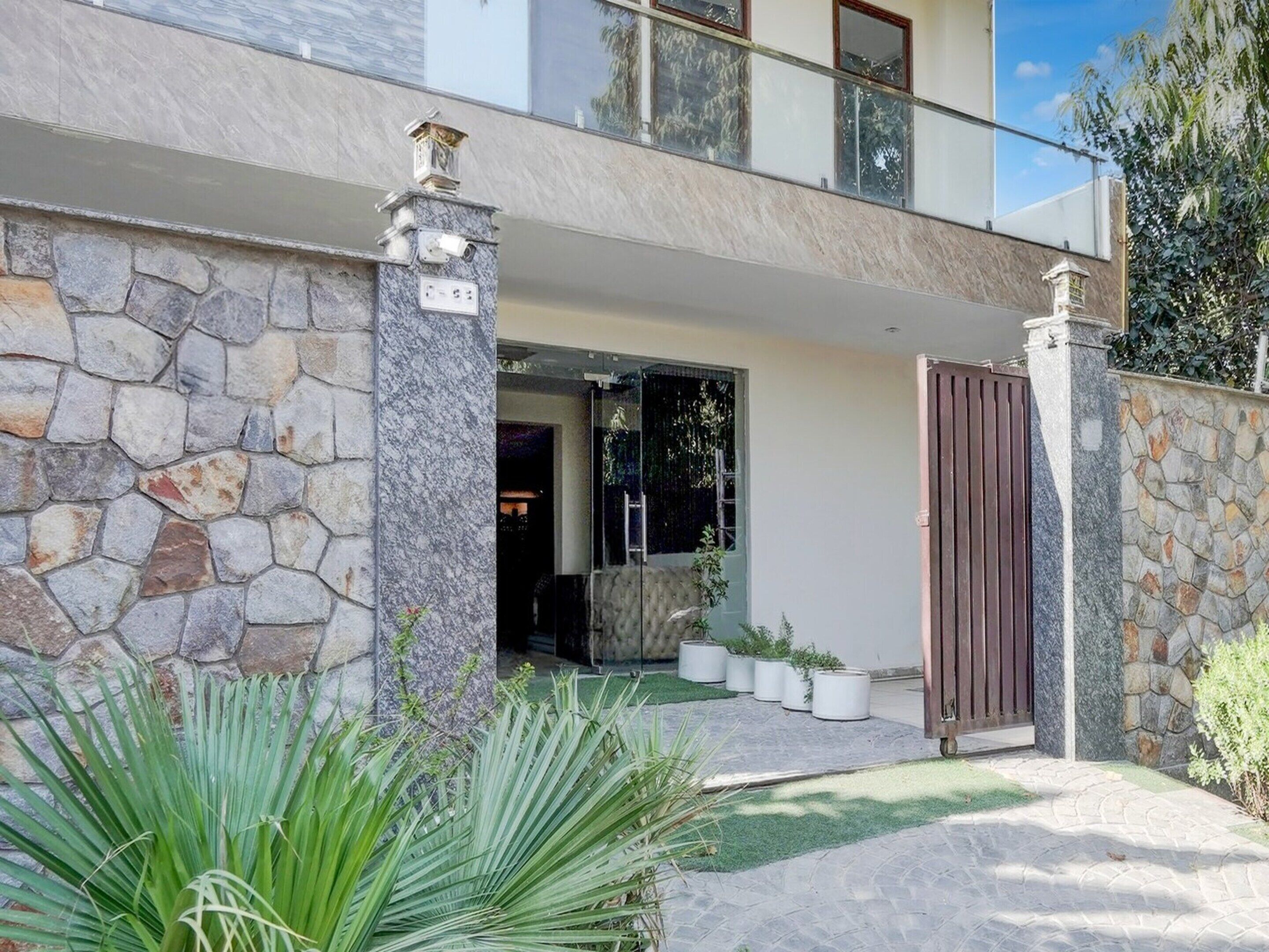 A two-story house with a stone facade, a gated entrance, and a balcony.