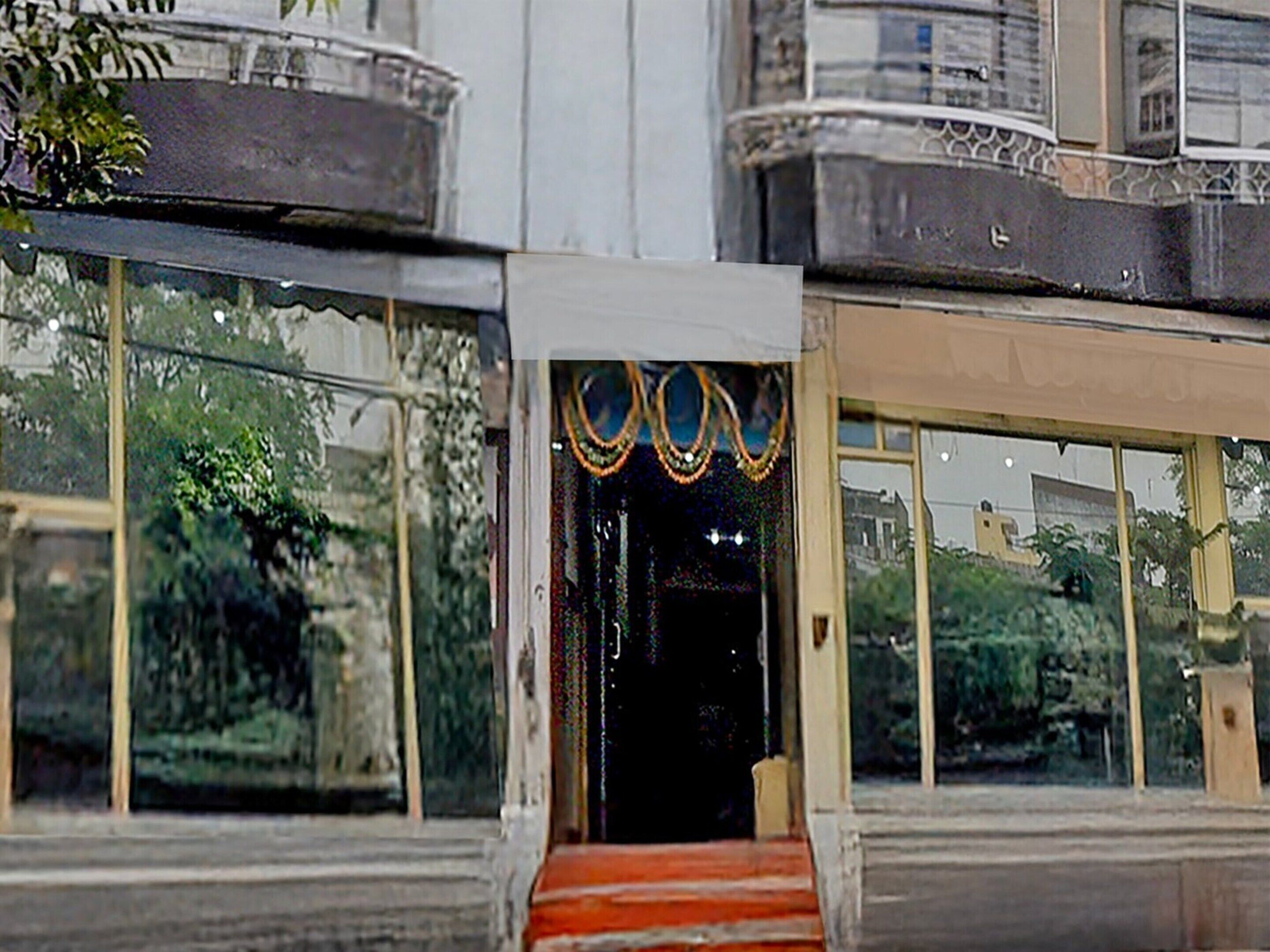 L’entrée d’un immeuble, avec un escalier menant à une porte, le tout entouré de grandes fenêtres.