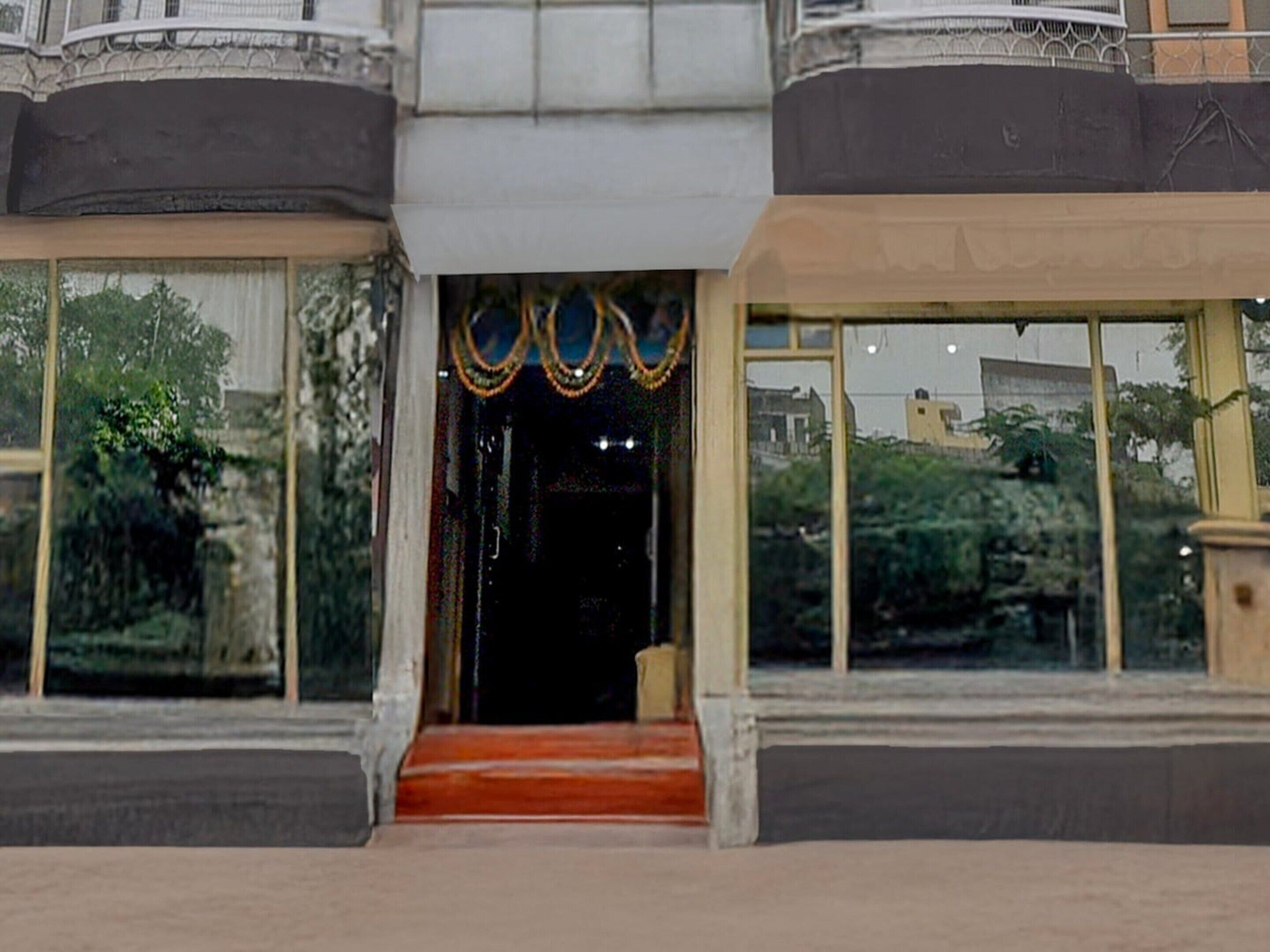 A building with a central entrance, large windows, and a red carpet leading to the door.