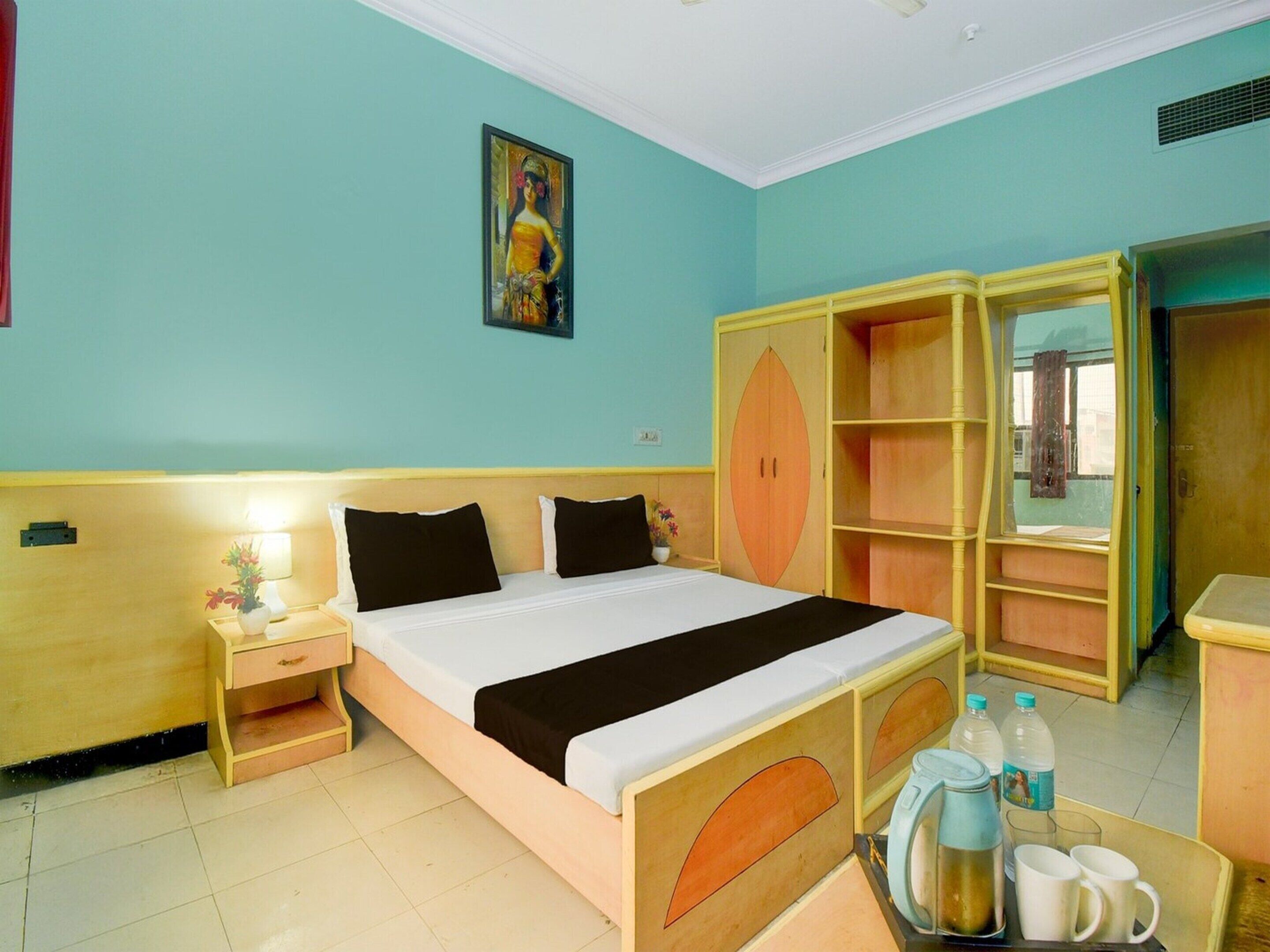 A bedroom with a bed, bedside table, nightstand, wardrobe, and a window.