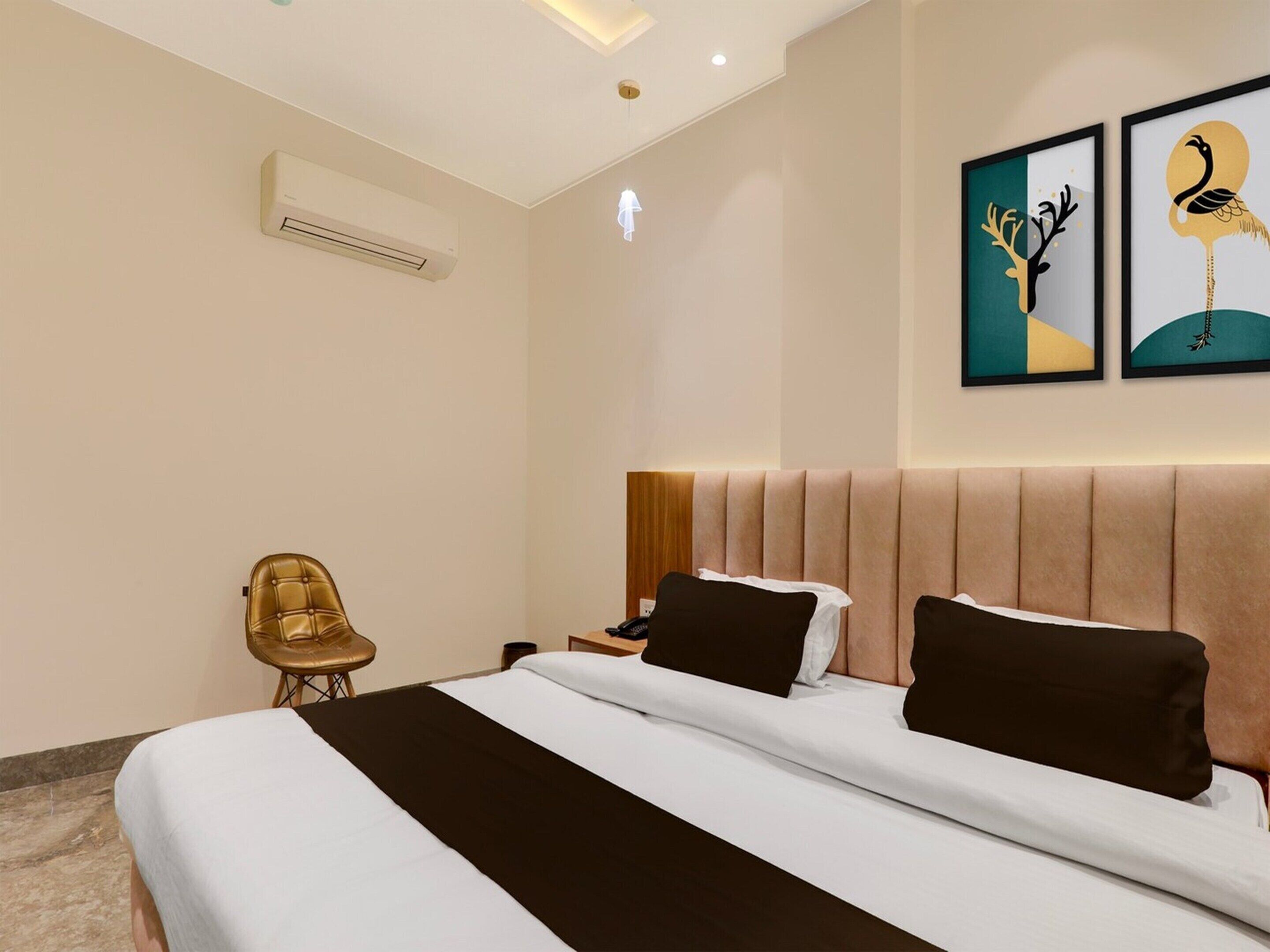 Une chambre d’hôtel comprenant un lit, une chaise, une table de chevet et deux œuvres d’art accrochées au mur.