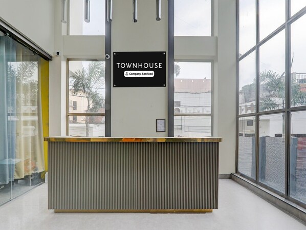En receptionsdisk märkt med texten ”TOWNHOUSE” och en skylt med företagets logotyp, stora fönster och utsikt över omgivningen.