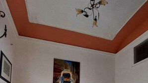 Un salon avec un plancher en bois, un canapé rouge, un tableau et un téléviseur.