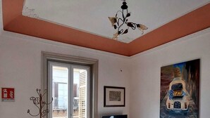 Un salon équipé d’un téléviseur, d’un tableau, d’un extincteur et d’une porte donnant sur un balcon.
