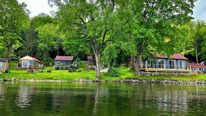 A lakeside cabin area with multiple cabins, a dock, and a grassy area with a hammock.