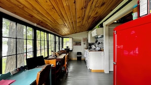 Een interieur van een blokhut met een eethoek, keuken en grote ramen.