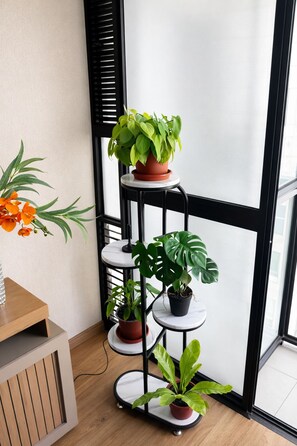 A multi-tiered plant stand with various potted plants. - Modern 2-room apartment in Lince | Prime location (Lince)