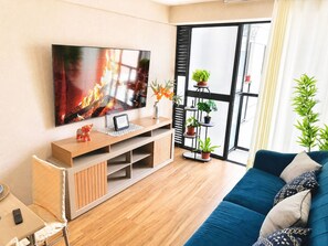 A living room with a flat-screen TV, wooden entertainment unit, blue sofa, and potted plants. - Modern 2-room apartment in Lince | Prime location (Lince)