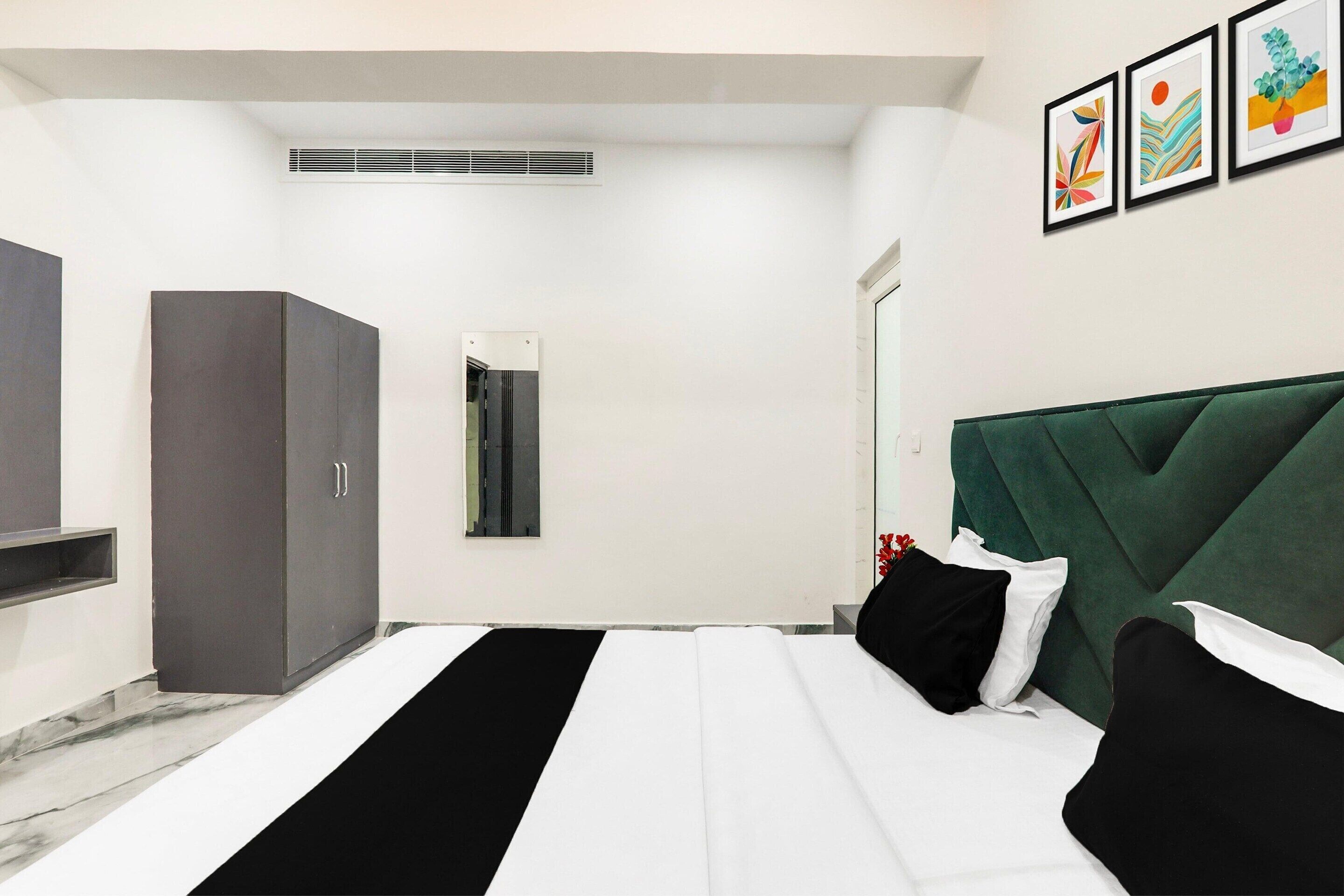 Een moderne hotelkamer met een bed, een kledingkast, een spiegel en een wandairconditioner.