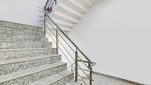 Una escalera con escalones de granito y barandillas de metal.
