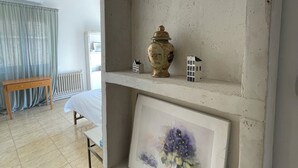 Et værelse med en hvid reol, en vase, et miniaturehus og et indrammet maleri.