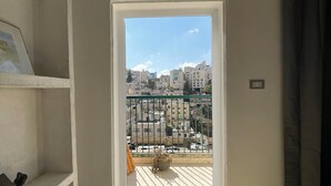 Et værelse med en dør til en balkon med udsigt over byen.