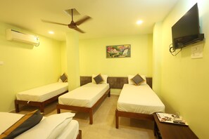 A hotel room with three single beds, a ceiling fan, an air conditioning unit, a flat-screen TV, and a painting on the wall.
