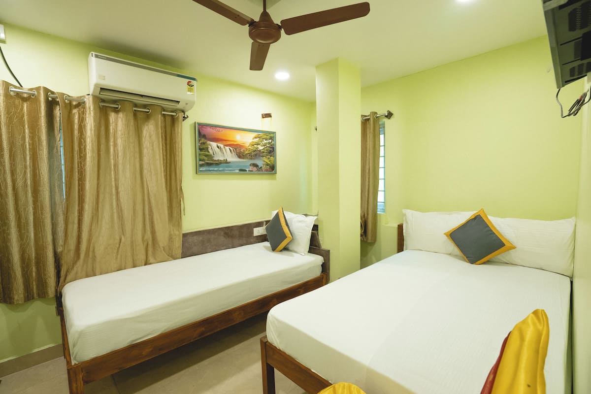 A room with two beds, a ceiling fan, an air conditioner, and a painting on the wall.