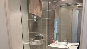 Un baño moderno con cabina de ducha de vidrio, un lavabo con espejo y una toalla colgada en la pared.