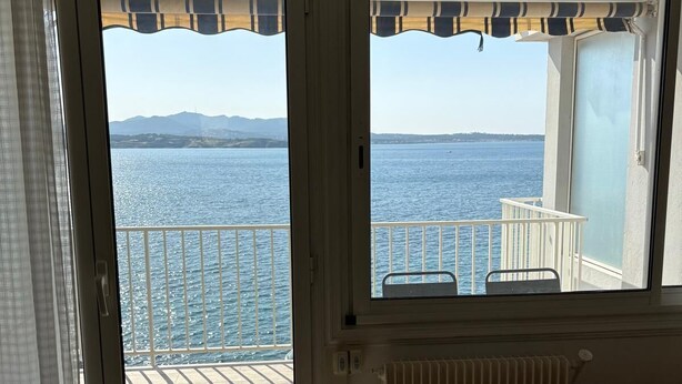 Habitación con vistas al mar a través de un ventanal corredera, un radiador y un sofá.