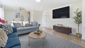 A living room with a sofa, coffee table, TV, and a plant. - Duplx 6BD-3BH- 3 Parking (West New York)