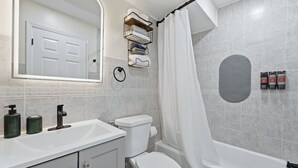 A bathroom with a white sink, toilet, and bathtub. There is a towel rack above the toilet and a shower curtain. - Duplx 6BD-3BH- 3 Parking (West New York)
